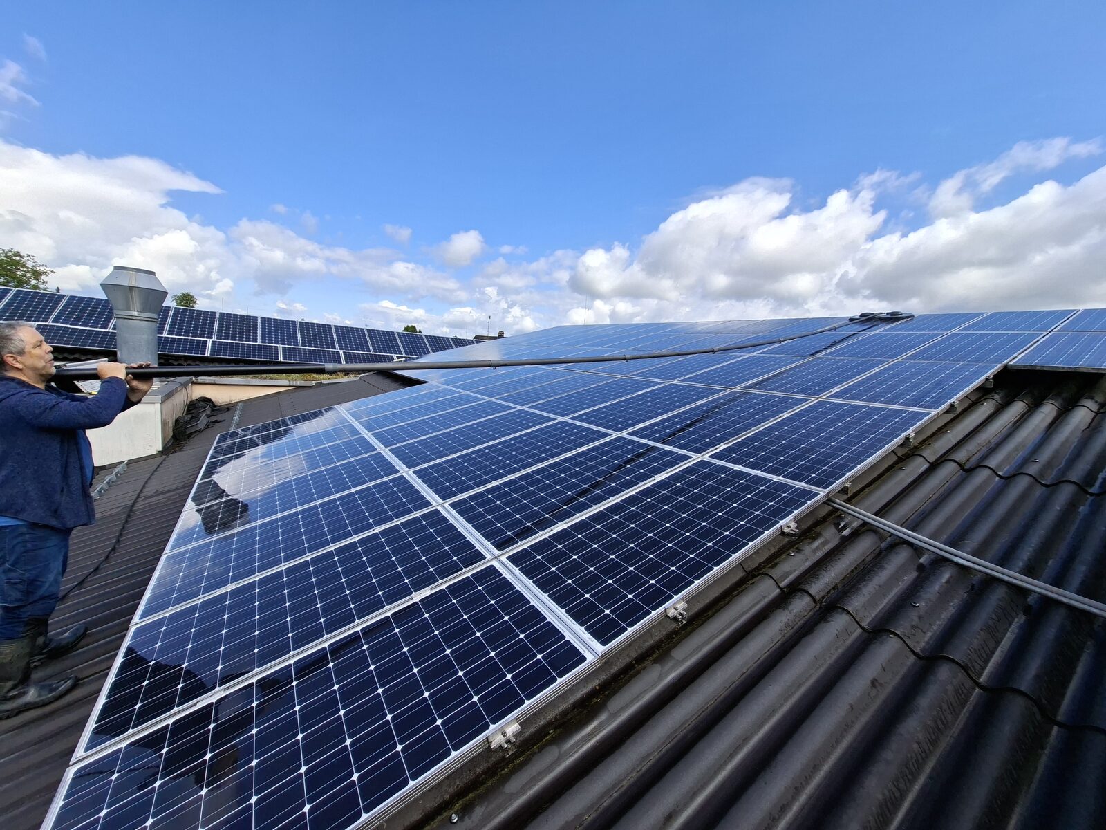 Workers cleaning photovoltaic solar panels with water spray