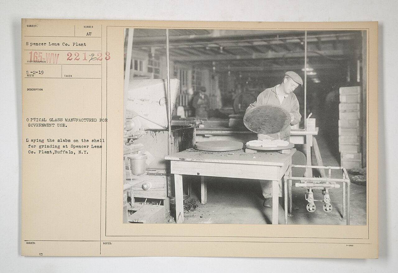 Optical glass slabs being placed on grinding shells at Spencer Lens Company plant during WWII-era optical lens manufacturing, public domain NARA photograph